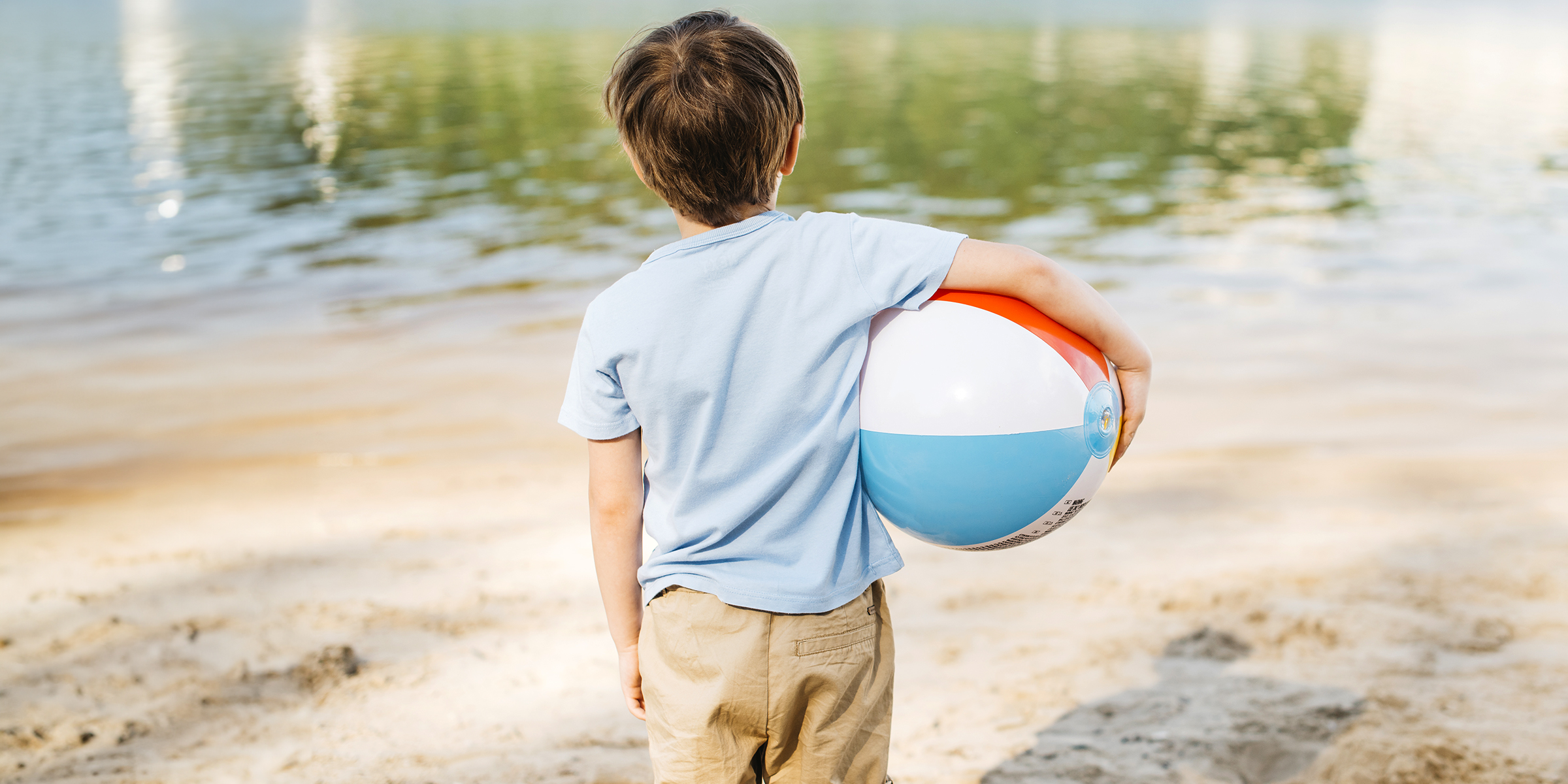 A little boy holding a ball on the beach | Source: Freepik