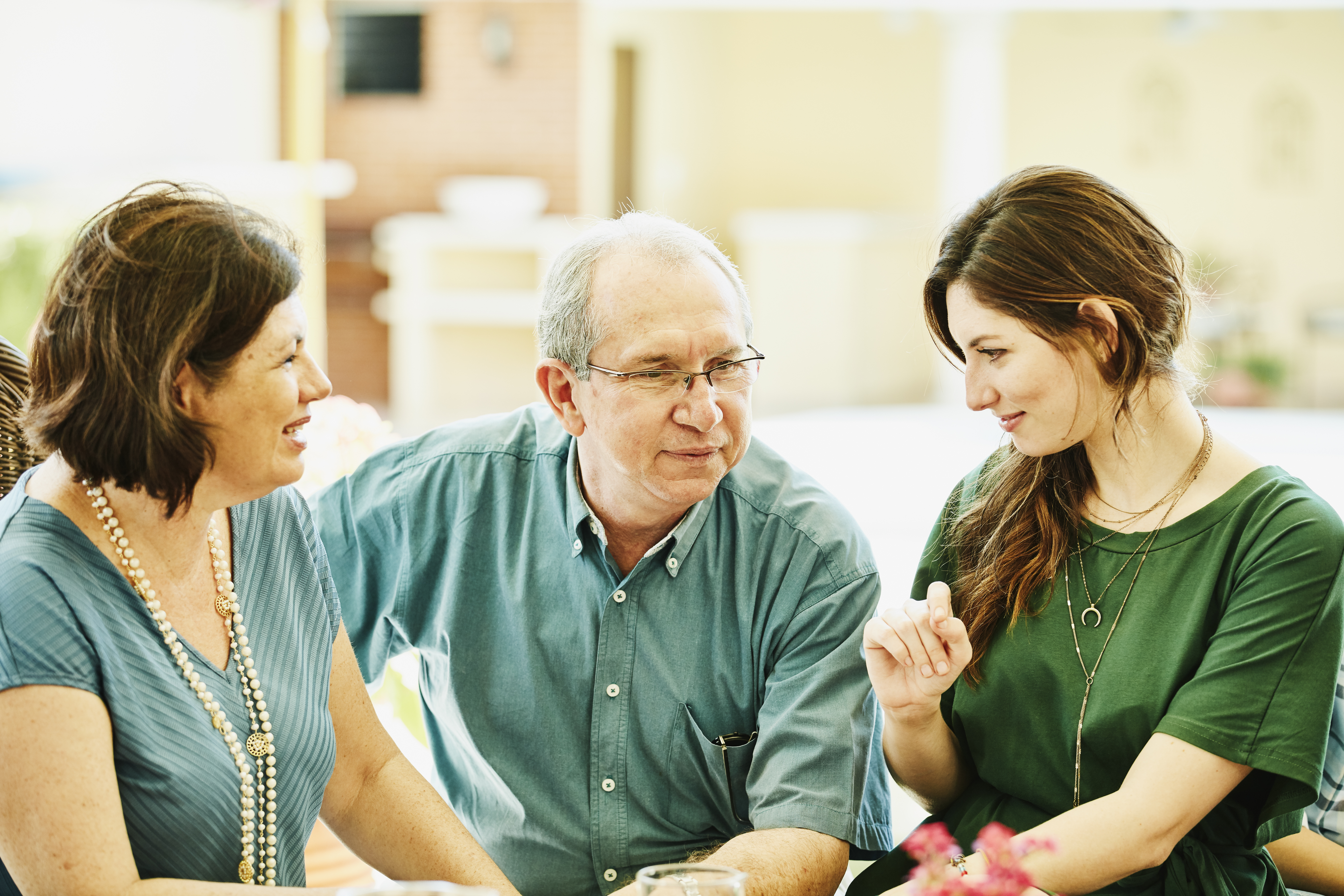 A happy father and daughter sitting with another woman | Source: Getty Images